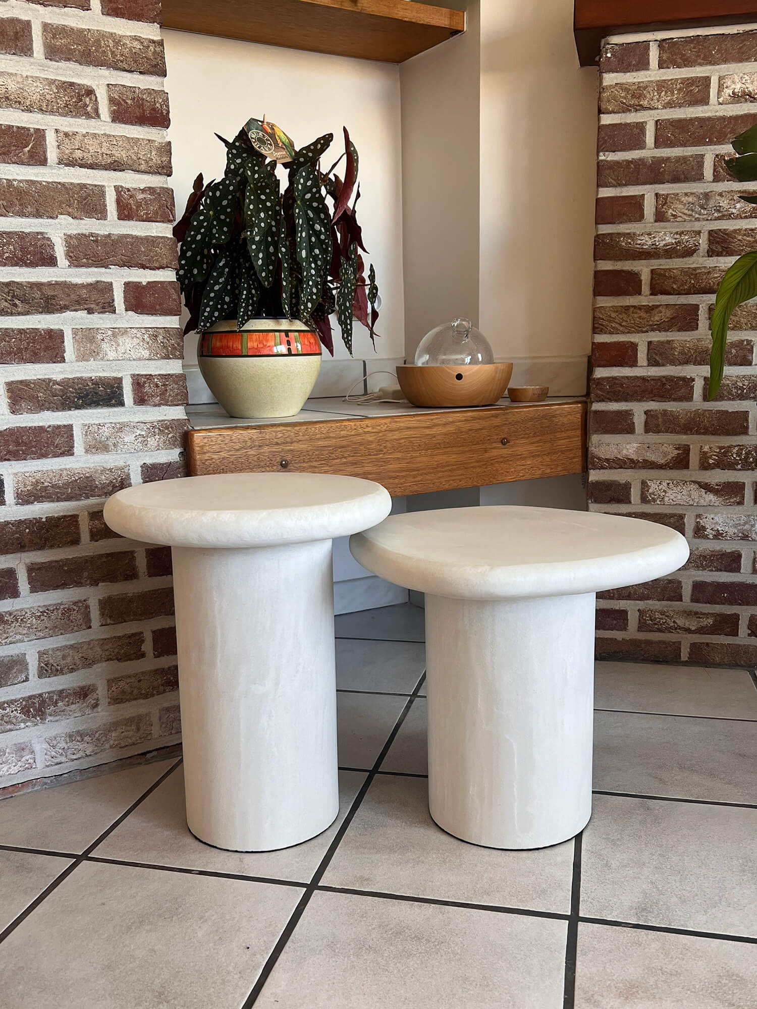 deux tables d'appoint en micro ciment mortex® posées devant un murs en brique chez une cliente en Belgique