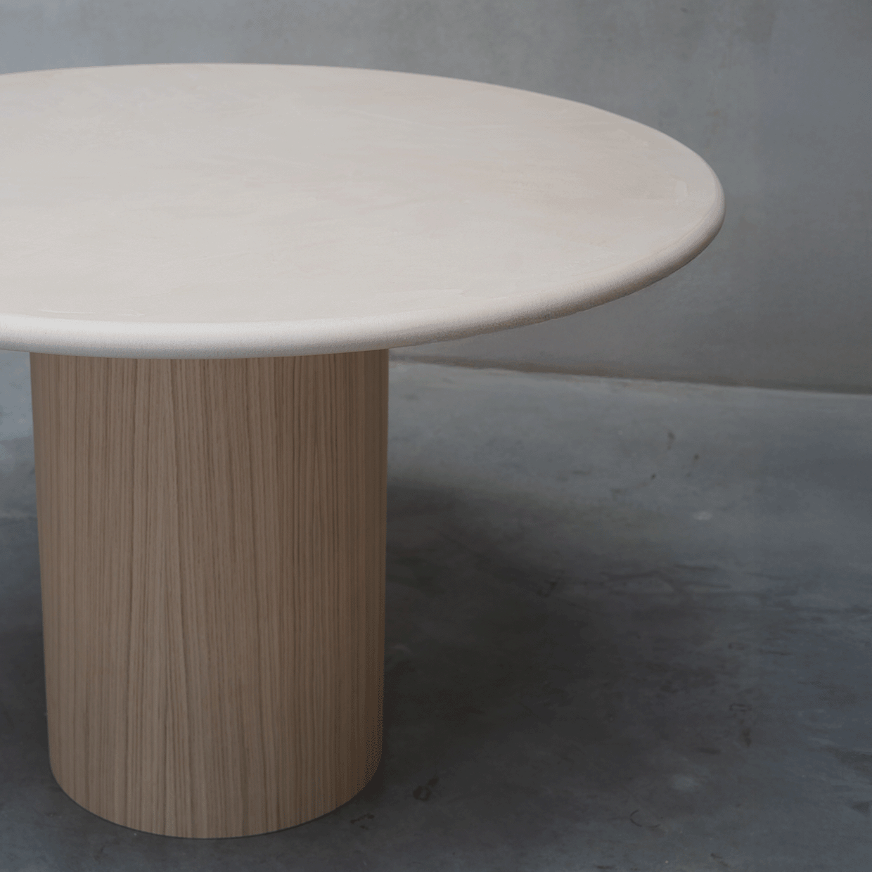 Détail du plateau fin en MORTEX® et du piètement en chêne de la table ronde Naya